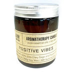 Brown glass jar labeled "Aromatherapy Candle Positive Vibes" with silver lid, made with clary sage and peppermint essential oils.