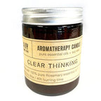 Aromatherapy candle in a dark glass jar with silver lid, labeled "Clear Thinking," made with pure rosemary essential oil and soy wax.
