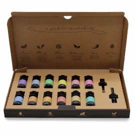 Set of assorted essential oils in a brown cardboard box, lid open to display 12 colorful 5 ml bottles neatly arranged in rows. Includes two black droppers. The inside lid features a printed guide to oil categories (citrus, minty, floral, herbaceous, spicy, woody).