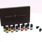 Set of essential oils with 12 small bottles displayed in front of a black box labeled “Essential Oils Set Aromatherapy,” accompanied by two glass droppers.