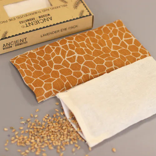 An eye-level shot showing the components of the aromatherapy eye pillow set. The main pillow has a giraffe pattern, and inside to it there is a  bag containing wheat seeds, lavender is a key of ingredient for the aromatherapy and home fragrance benefits.