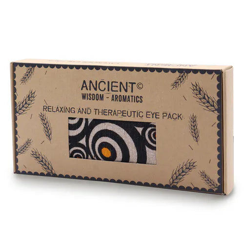 A product shot of a brown cardboard gift box for an aromatherapy eye pillow with a striking black, white, and orange spiral pattern. The box is clearly labeled "Ancient Wisdom - Aromatics" and "Relaxing and Therapeutic Eye Pack," promoting a soothing home fragrance and aromatherapy experience.