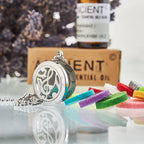 Round silver essential oil diffuser pendant with a cut-out design of musical notes, shown with colorful felt pads and an oil bottle in the background.