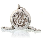 Close-up of a round silver essential oil diffuser pendant featuring a cut-out design of musical notes, displayed with a chain.