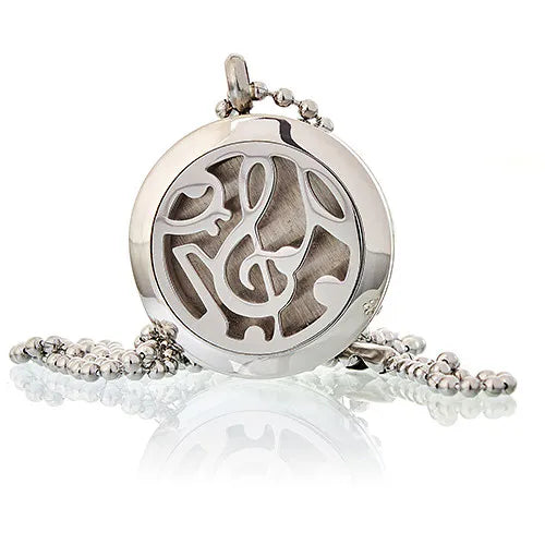 Close-up of a round silver essential oil diffuser pendant featuring a cut-out design of musical notes, displayed with a chain.