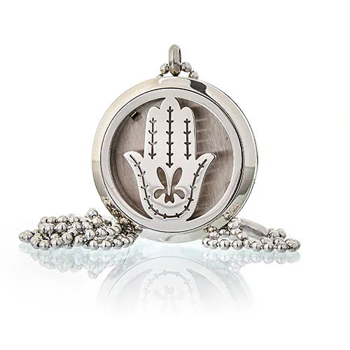 Silver essential oil diffuser necklace pendant featuring a Hamsa hand design, displayed on a reflective surface with a ball chain.
