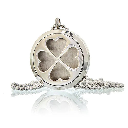 Close-up of silver essential oil diffuser pendant with four-leaf clover heart design on a ball chain.