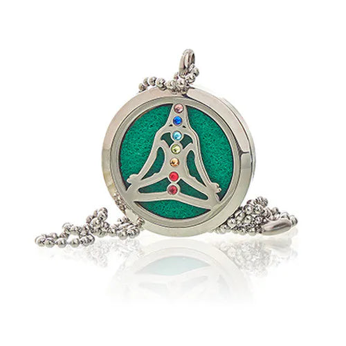 Stainless steel aromatherapy diffuser necklace featuring a meditating yoga figure with chakra-colored crystals with a green felt pad inside.