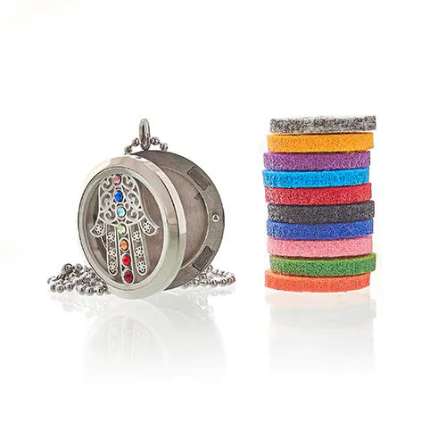 Silver Hamsa hand aroma diffuser pendant with multicolored gemstones, shown standing next to a stack of colorful felt pads.