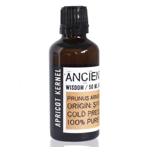 Amber glass bottle labeled “Ancient Wisdom / 50 ml Base Oil.” The label highlights “Prunus Armeniaca” (Apricot Kernel oil), origin Spain, cold pressed, and 100% pure oil. The main label section is beige-golden with bold black text, while the vertical side strip reads “APRICOT KERNEL” in white on a black background. The bottle is sealed with a black ribbed screw cap, giving it a clean and natural apothecary-style presentation.