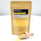 Kraft paper pouch with yellow bath salts, labeled "Ancient Wisdom Aromatherapy Bath Potion – Wake Up", shown with a small wooden scoop filled with salts.