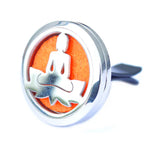 Close-up of a silver car air diffuser with an intricate cut-out design of a meditating Buddha sitting on a lotus flower. The bright orange felt pad inside adds a vibrant and energizing touch, symbolizing balance and mindfulness while keeping the car fresh.