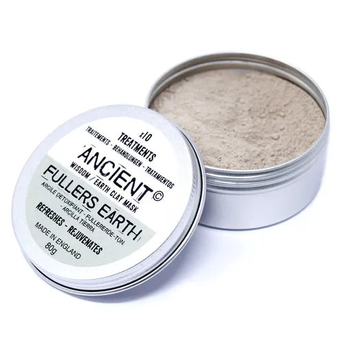 Open tin of Ancient Wisdom Fullers Earth Clay Mask showing light beige clay powder inside. The container rests with its lid tilted, displaying the white and pale green label that emphasizes its skin-refreshing and rejuvenating qualities.