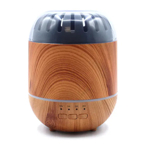 A product shot of a small, rounded essential oil diffuser with a light wood grain base and a dark, clear top with vents. The base has timer and power buttons and is on a white background.