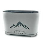 Close-up of a modern, rectangular white aroma diffuser with a black mountain silhouette design on the front and four control buttons below, placed on a white background.