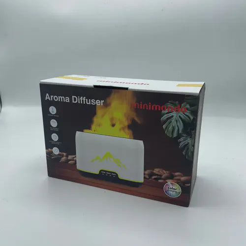 Box packaging of a "Minimondo" aroma diffuser showing the product with a glowing flame effect, mountain silhouette design, and control buttons; the box includes icons for features like adjustable light and automatic safety shut-off.