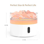 Round white aroma diffuser with transparent top filled with pink crystal-like stones, illuminated with warm orange light, dimensions 4.2 inches tall and 4.7 inches wide shown in the image.
