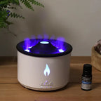 White cylindrical aroma diffuser with glowing blue light and mist effect from the top, placed on a wooden surface next to a lavender essential oil bottle.