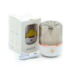 White round mirror aromatherapy humidifier placed next to its packaging box and USB charging cable.