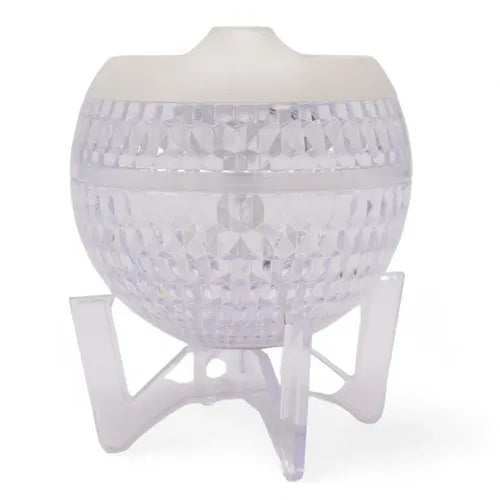 Transparent faceted spherical aroma diffuser with a white lid, placed on a clear tripod stand, turned off.