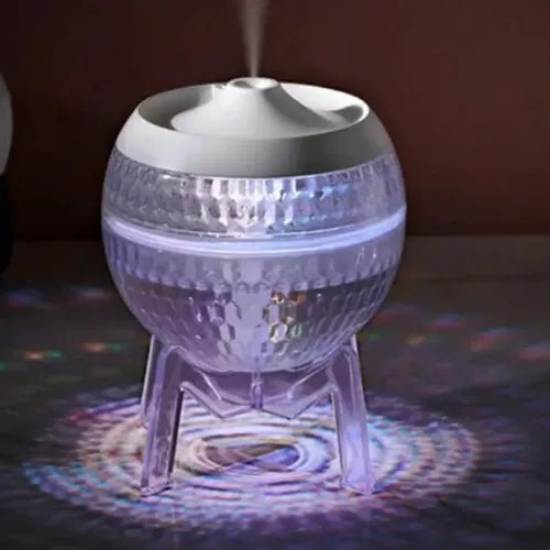 Crystal-like spherical aroma diffuser with a white lid, emitting mist and illuminated with cool blue and purple LED lights.