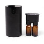 Black cylindrical aroma diffuser with two amber glass bottles connected to the upper module.