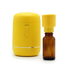 Yellow essential oil diffuser next to an amber essential oil bottle with yellow cap.