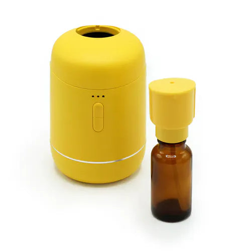 Yellow essential oil diffuser with detachable amber glass bottle placed beside it.