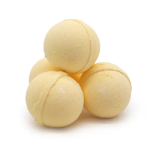 Four pale yellow spherical bath bombs placed in a pyramid stack, showing a powdery finish with subtle seam lines, photographed on a bright white background.