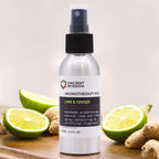 Silver spray bottle of Ancient Wisdom Aromatherapy Mist labeled "Lime & Ginger," displayed with fresh lime halves and ginger roots.