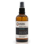 Brown glass spray bottle labeled "Ancient Wisdom Facial Toner Mist Cooling Peppermint," with a black spray cap and white label. The label highlights peppermint and witch hazel as ingredients, designed for refreshing and soothing all skin types.