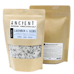 Brown kraft pouch of Ancient Wisdom Himalayan Bath Salt Lavender & Seeds, relaxing artisan formula with essential oils, jojoba oil, and lavender seeds; coarse white salt mixed with visible lavender pieces.