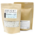 Brown kraft pouch of Ancient Wisdom Himalayan Bath Salt Rosemary & Clary Sage, clarity blend infused with essential oils, olive oil, and rosemary herb; pale salt with small green herbal fragments visible.