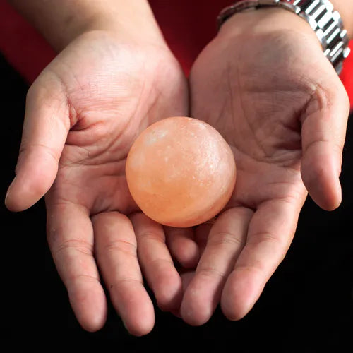 Hands holding a round Himalayan pink salt deodorant stone.