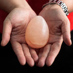 Hands holding an egg-shaped Himalayan pink salt deodorant stone.