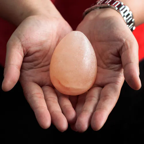 Hands holding an egg-shaped Himalayan pink salt deodorant stone.