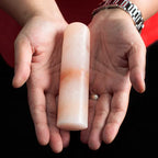 Hands holding a cylindrical Himalayan pink salt deodorant stone.