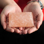 Hands holding a rectangular Himalayan pink salt deodorant stone.