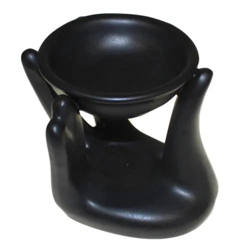 Matte black ceramic oil burner styled as a sculpted hands lifting a shallow bowl, suitable for aromatherapy oils or wax melts.
