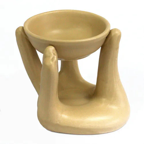 Tan ceramic oil burner in the shape of a stylized hands holding up a round shallow bowl, designed for use with essential oils or wax melts.