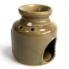 Rear view of a brown glazed ceramic oil burner with a glossy finish. The back features round ventilation holes near the top and a large arched opening at the base for placing a candle.