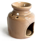 Rear view of a beige glazed ceramic oil burner with glossy finish. The back shows two round ventilation holes and a large arched cut-out at the bottom for a candle.