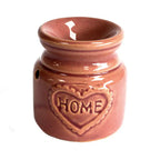 Front view of a rose ceramic oil burner with glossy finish and heart-shaped embossed design containing the word “HOME.” The item has a compact, rounded shape with decorative ventilation holes.