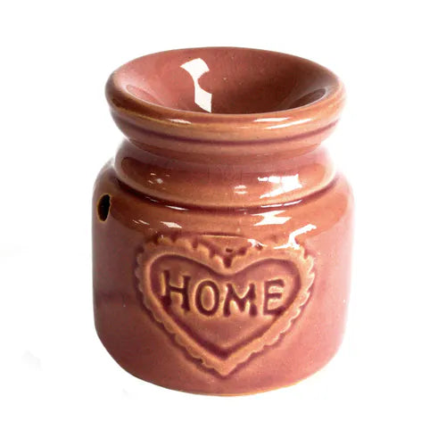 Front view of a rose ceramic oil burner with glossy finish and heart-shaped embossed design containing the word “HOME.” The item has a compact, rounded shape with decorative ventilation holes.