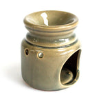 Brown glazed ceramic oil burner viewed from the side, showing the open cavity at the bottom designed to hold a tealight candle, along with circular cut-out holes for ventilation and light dispersion.