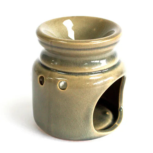 Brown glazed ceramic oil burner viewed from the side, showing the open cavity at the bottom designed to hold a tealight candle, along with circular cut-out holes for ventilation and light dispersion.