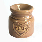 Beige ceramic oil burner with a glossy crackle glaze, featuring a round bowl on top for essential oils or wax melts, and a heart-shaped relief on the front with the word "HOME" embossed in capital letters.