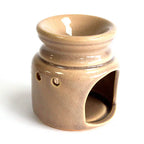 Side view of a beige ceramic oil burner with a glossy crackle glaze, showing the round top bowl for oils or wax melts, circular ventilation holes, and a large hollow opening at the base for a tealight.