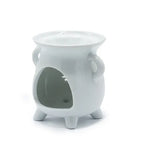 Side view of white ceramic oil burner, showing its hollow opening at the bottom where a tealight candle can be placed. The burner is glossy, with two side handles, three sturdy legs, and a wide shallow bowl on top for holding oil or wax. The cut-out decorative tree design is partially visible from the inner side, emphasizing both function and aesthetic detail.