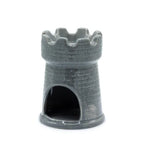Gray ceramic oil burner shaped like a medieval castle tower, with a rounded base and wide crenellated top rim. The surface is textured with a brick pattern, and there is a large arched opening at the bottom back to place a tealight candle inside. The glossy finish highlights the details of the faux stone design.